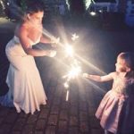 Bride playing with her daughter with sparklers at wedding